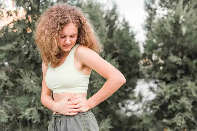 Colon Hydrotherapy Clearwater, Therapeutic Elements Center for Massage Therapy A woman outdoors that needs Colon Hydrotherapy holding her stomach