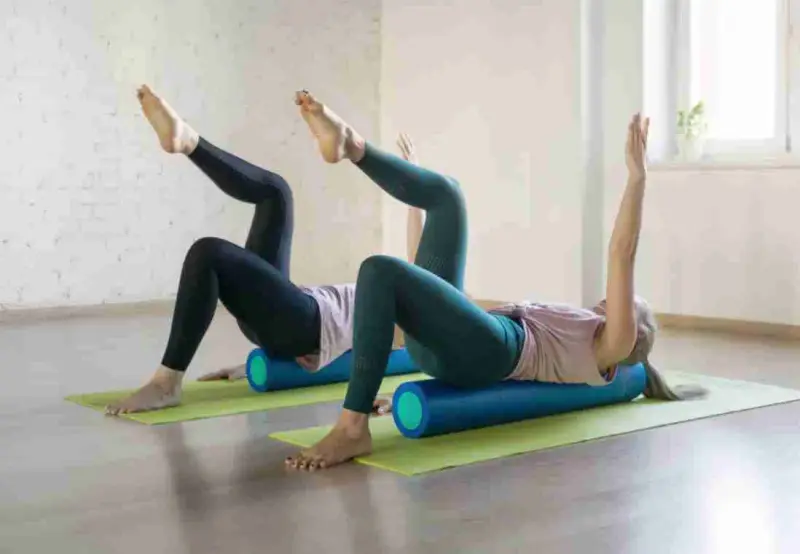 Two women on yoga mats doing a stretching class