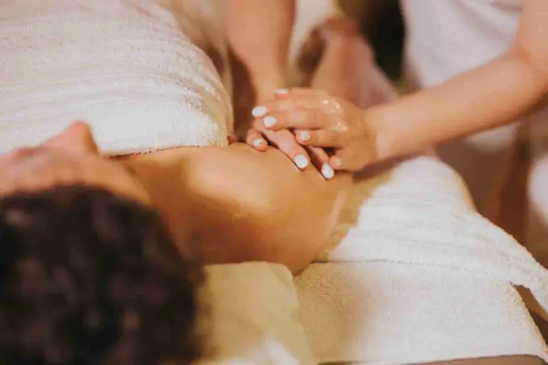 Female Massage preforming a massage service on a client who is properly draped on a massage table